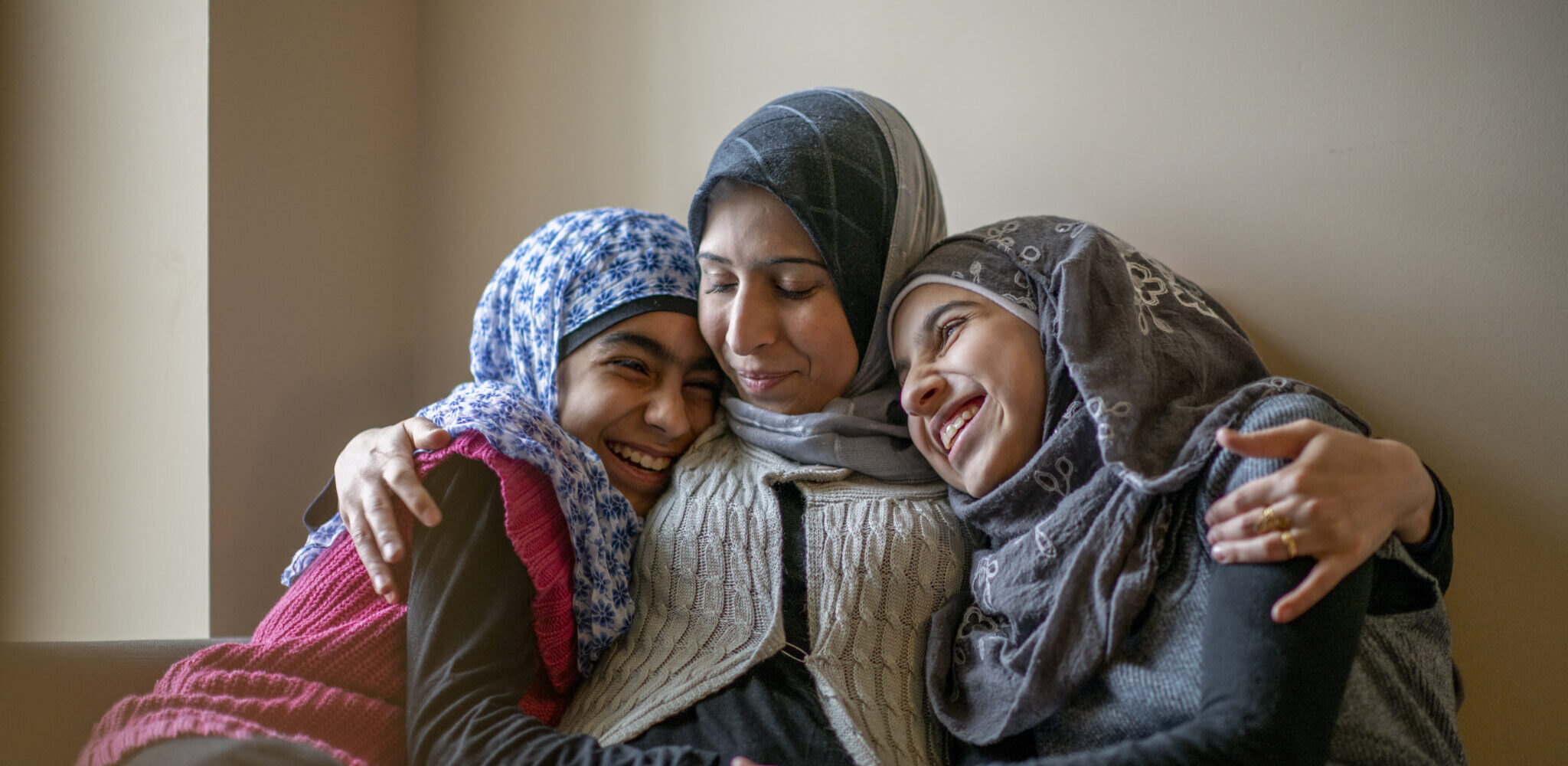 A Muslim mother hugs both her daughters in her arms.